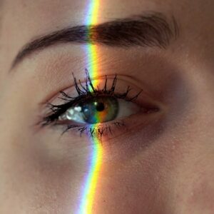 Oeil d'une femme traversé par le reflet d'un arc-en-ciel