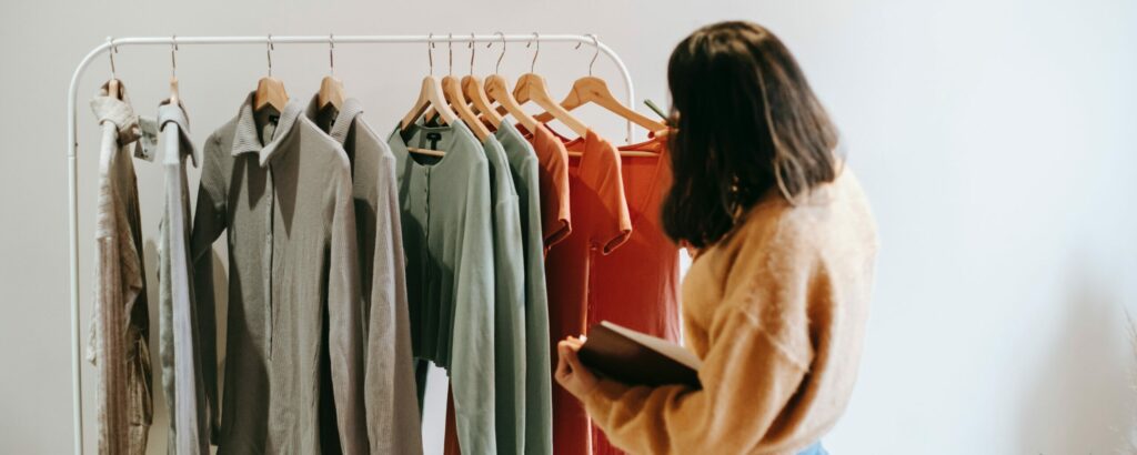 Femme qui effectue la vérification du classement de vêtements accrochés sur une tringle.