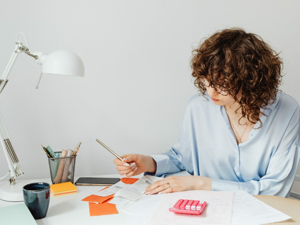 Jeune femme aux cheveux frisés bruns qui fait sa comptabilité