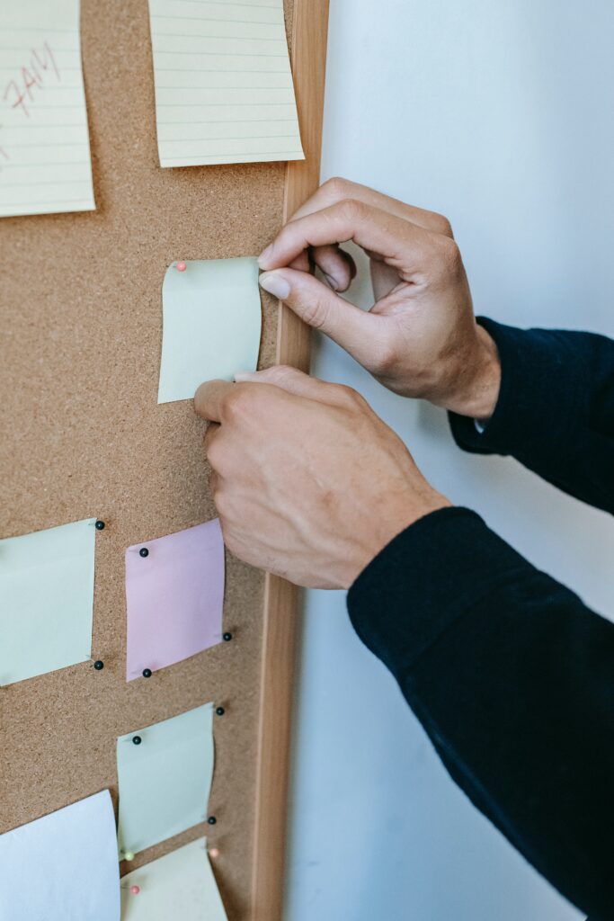 Mains d'homme qui mettent des post-it sur un tableau.