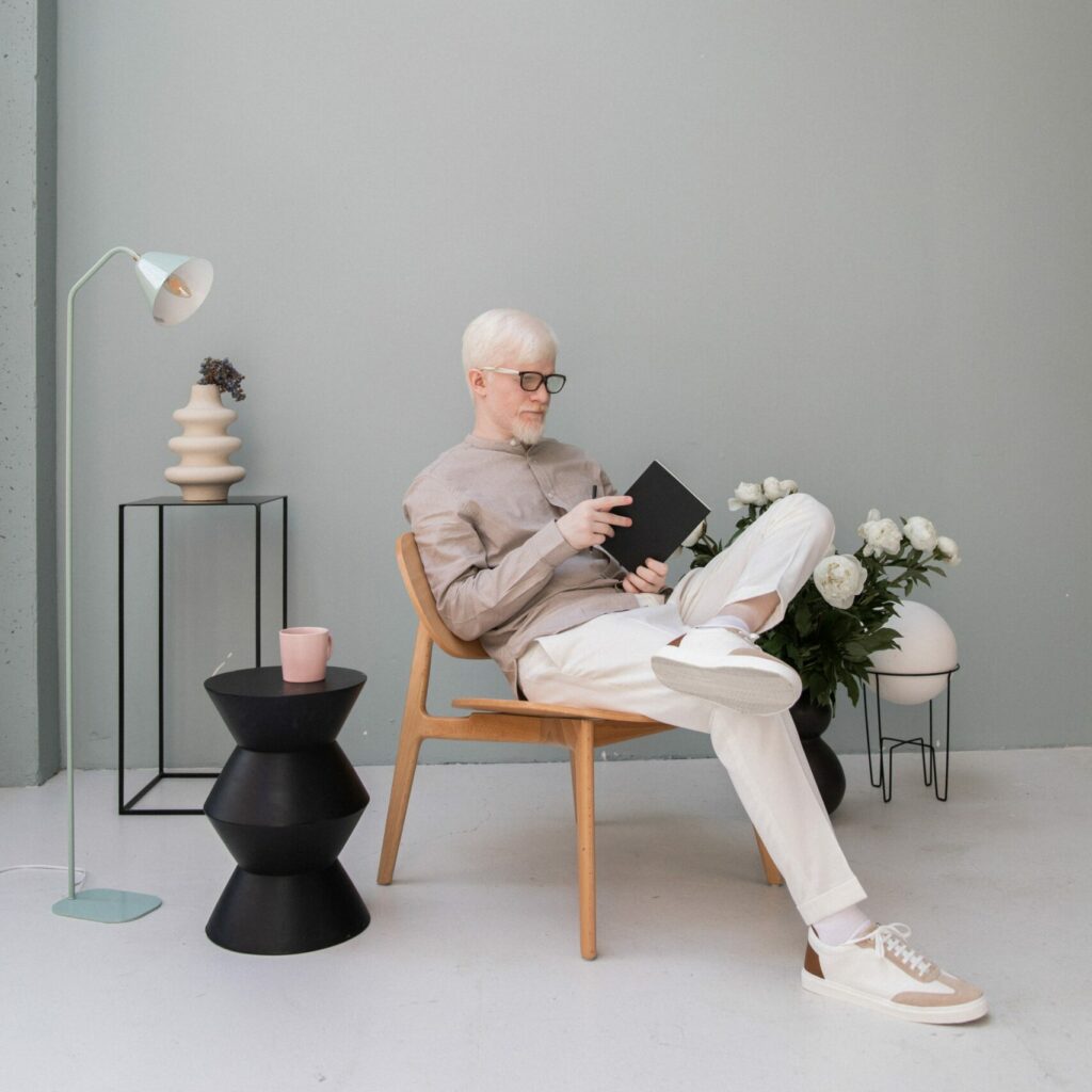 Homme âgé aux cheveux blancs qui fait de la lecture dans un décor minimaliste