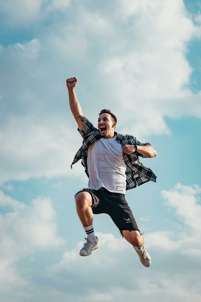 Un jeune homme est en mouvement. Il saute dans les airs et est joyeux.