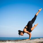 Une jeune femme fait du yoga en extérieur et se tient en équilibre.