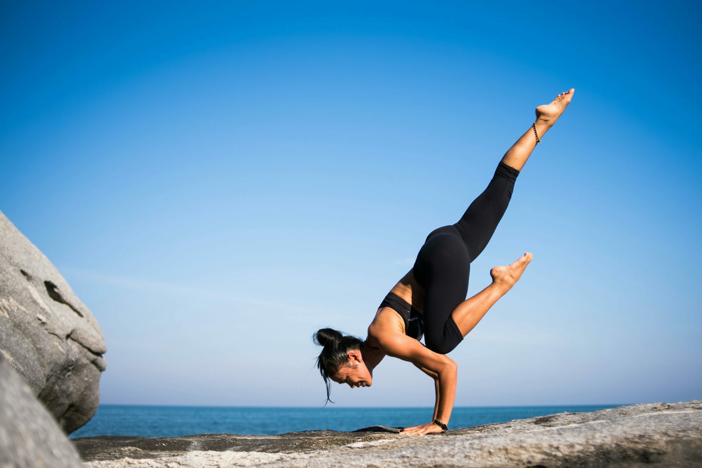 Une jeune femme fait du yoga en extérieur et se tient en équilibre.