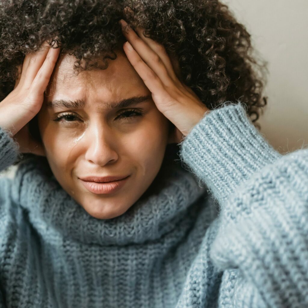 Une femme à la peau noire se prend la tête à deux mains puisque sa santé mentale ne va pas bien. 