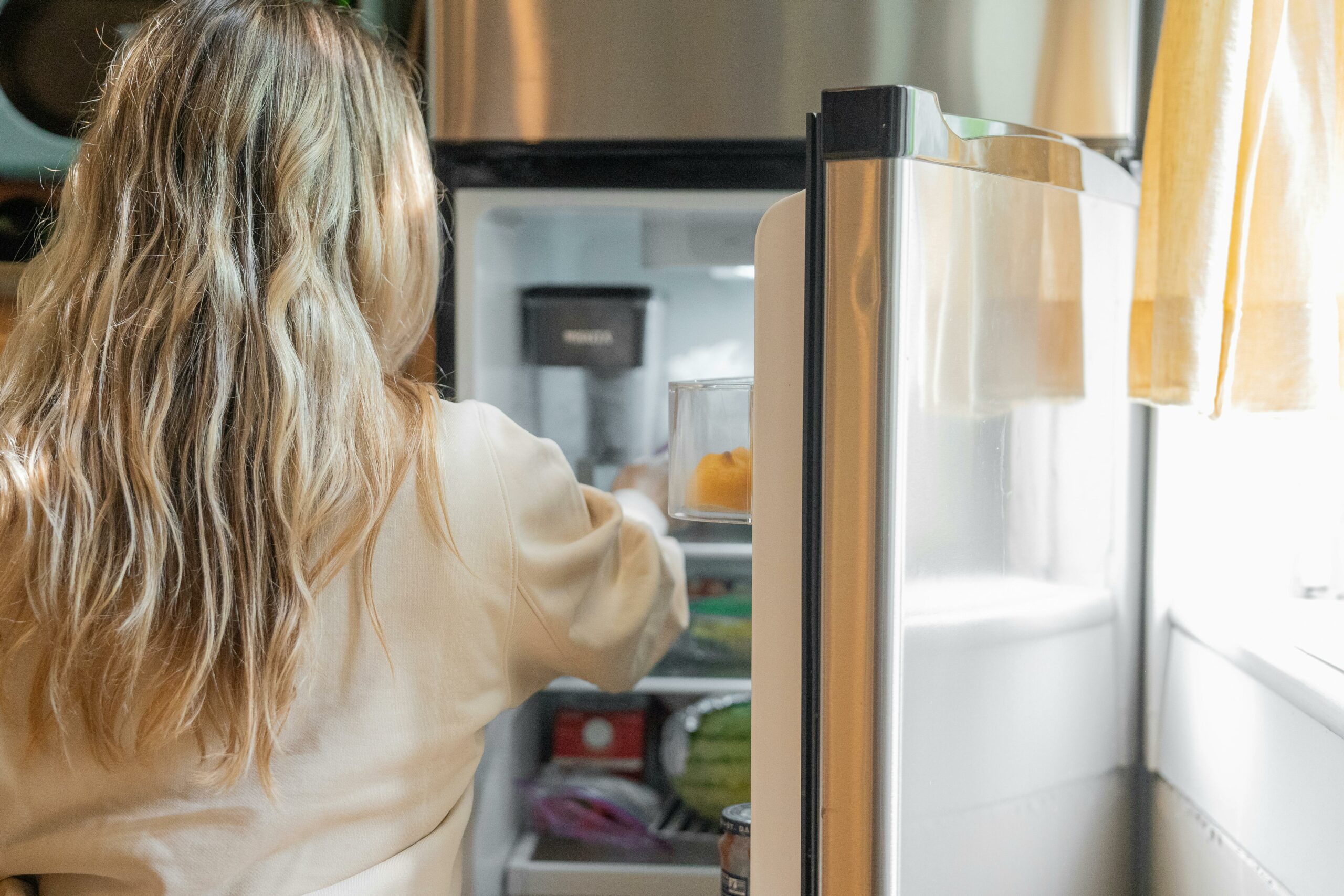 Femme qui range quelque chose dans son réfrigérateur