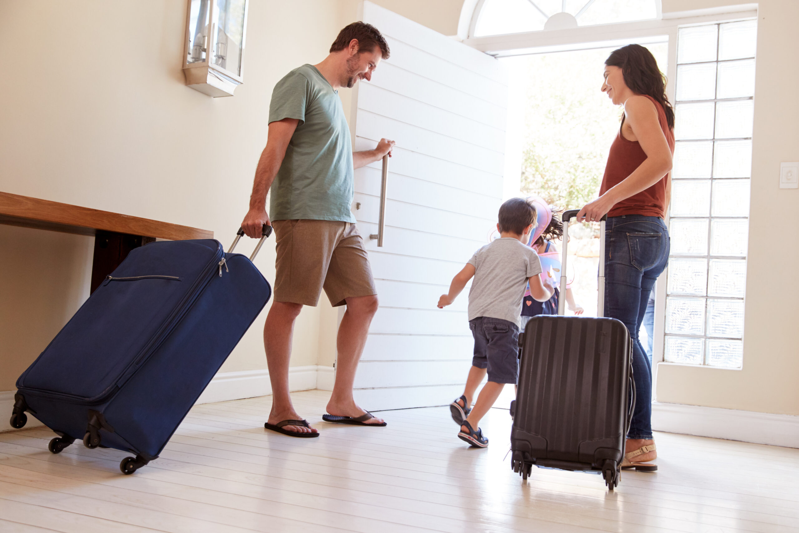 Une famille souriante quitte la maison avec des valises, illustrant les conseils de StéZen pour bien préparer sa maison avant les vacances et partir l’esprit tranquille.