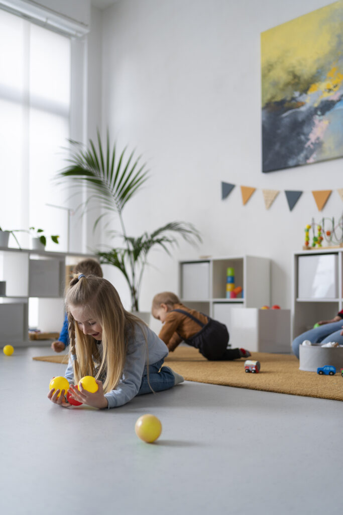 Des enfants jouent librement dans une pièce lumineuse et bien aménagée, illustrant les bienfaits d’une bonne organisation de la salle de jeux pour favoriser l’autonomie et le plaisir au quotidien.