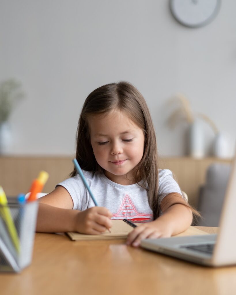 Petite fille concentrée à son bureau pour faire ses devoirs, dans un environnement organisé pour bien commencer la rentrée scolaire.