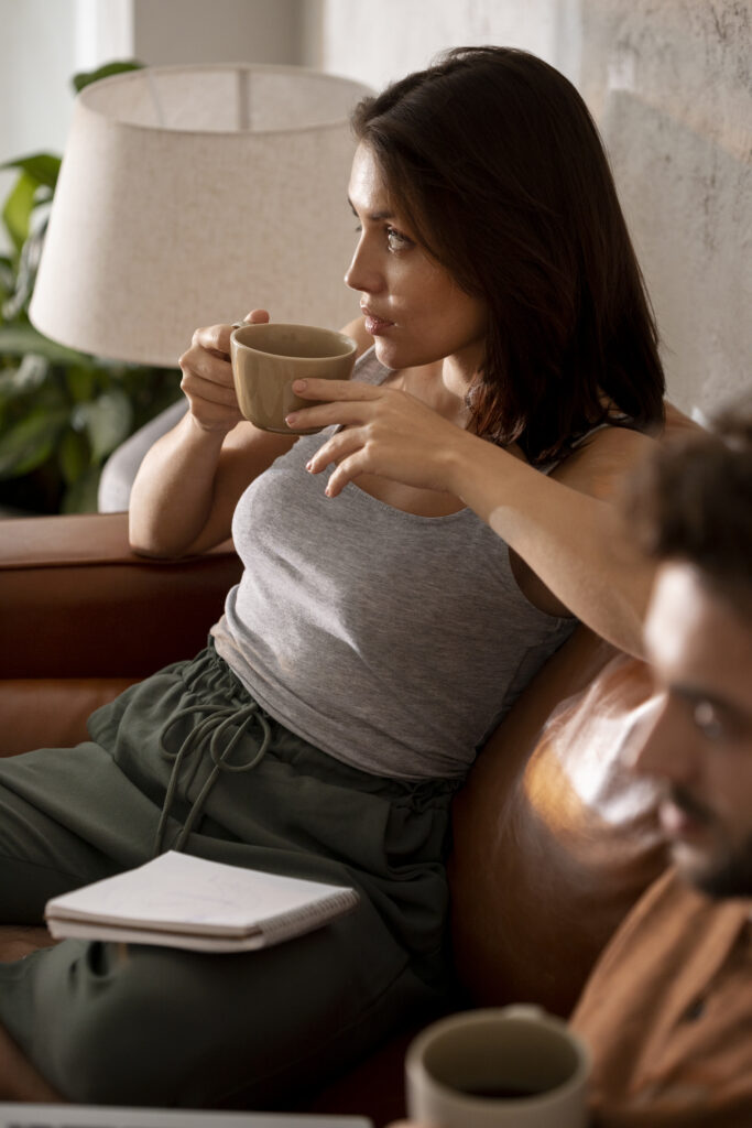 Femme en pleine pause-café dans son salon, un moment de calme essentiel pour alléger la charge mentale au quotidien.