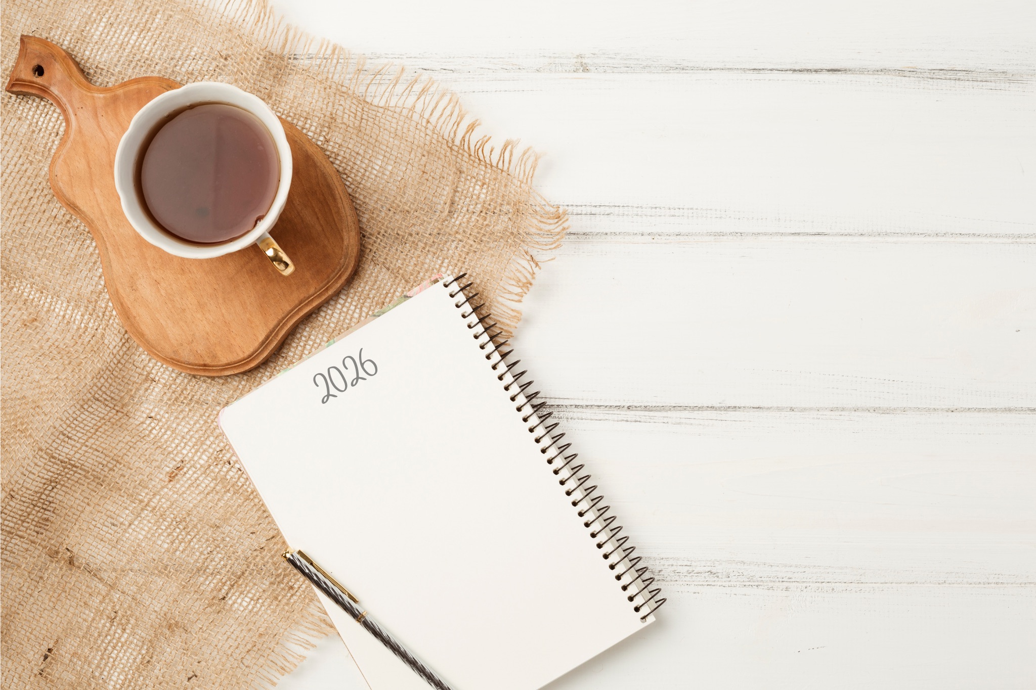 Cahier ouvert avec l’année 2026 écrite à la main, accompagné d’une tasse de thé, évoquant la réflexion, les intentions et l’alignement pour la nouvelle année.