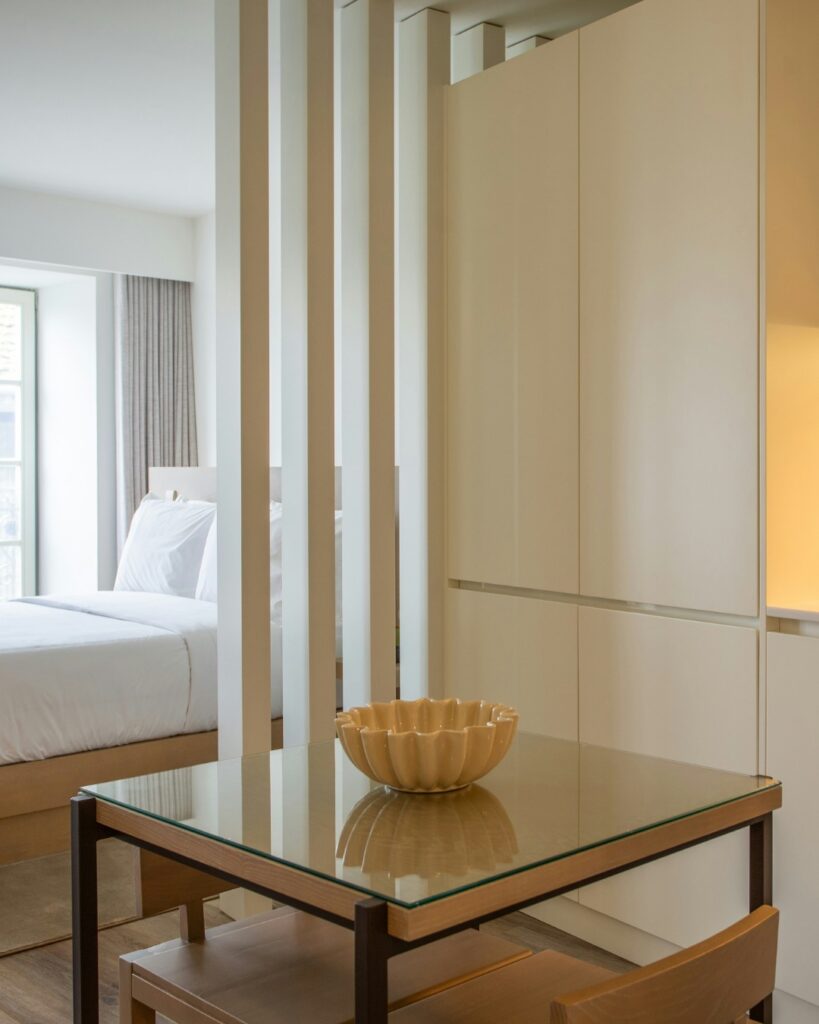 Studio organisé avec séparation en lattes entre la chambre et la cuisine, mobilier minimaliste et rangement intégré optimisant l’espace.