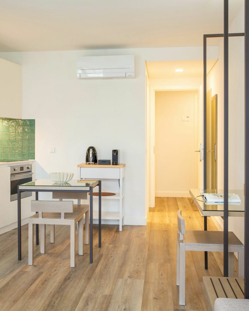 Petit espace de condo bien aménagé avec cuisine compacte, table à manger et coin travail, illustrant une organisation fonctionnelle et épurée.