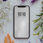 Téléphone cellulaire posé sur une surface blanche entourée de fleurs séchées colorées, image utilisée pour illustrer le désencombrement numérique et le ménage digital du printemps