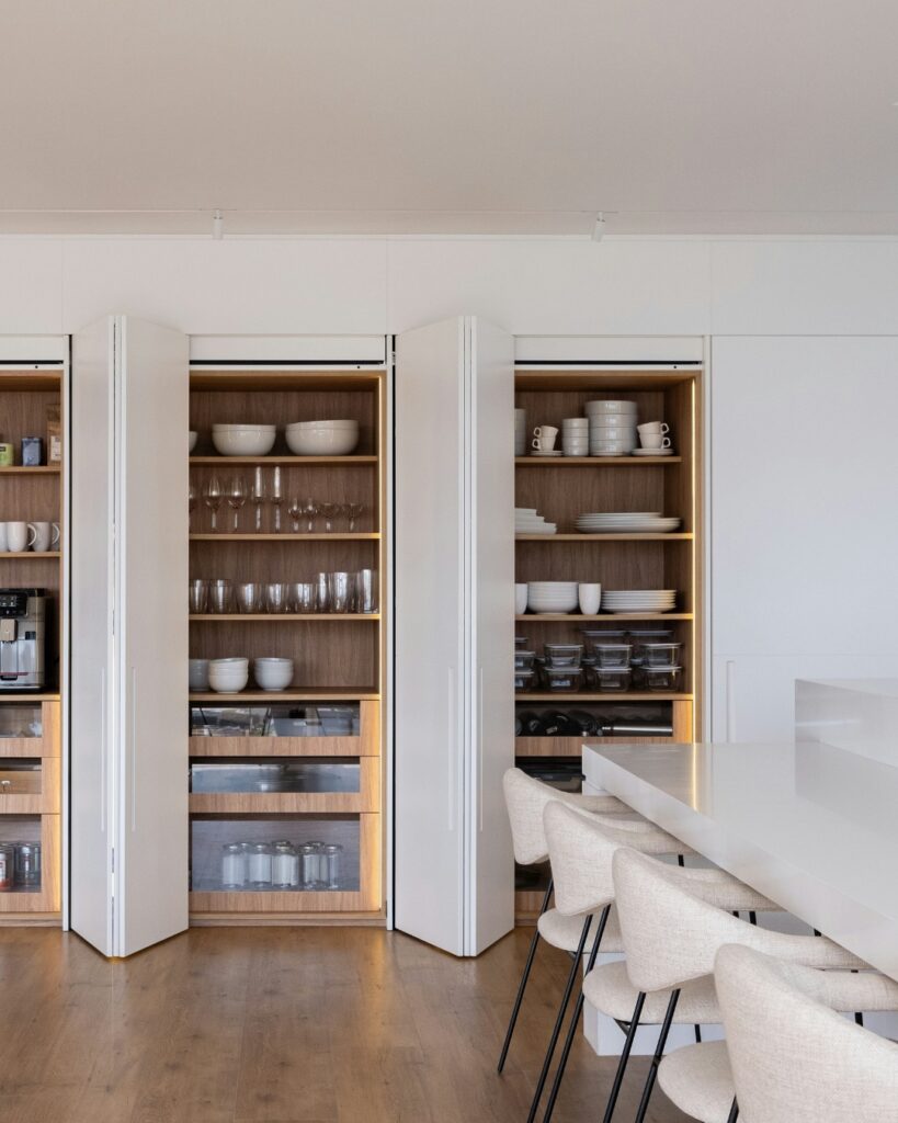 Cuisine organisée par une organisatrice professionnelle avec une vaisselle, des verres et des contenants soigneusement rangés.