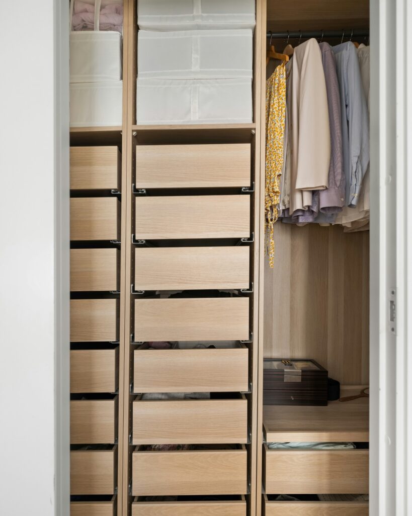 Garde-robe optimisé par une organisatrice professionnelle avec des tiroirs, des vêtements suspendus et des solutions de rangement sur mesure.