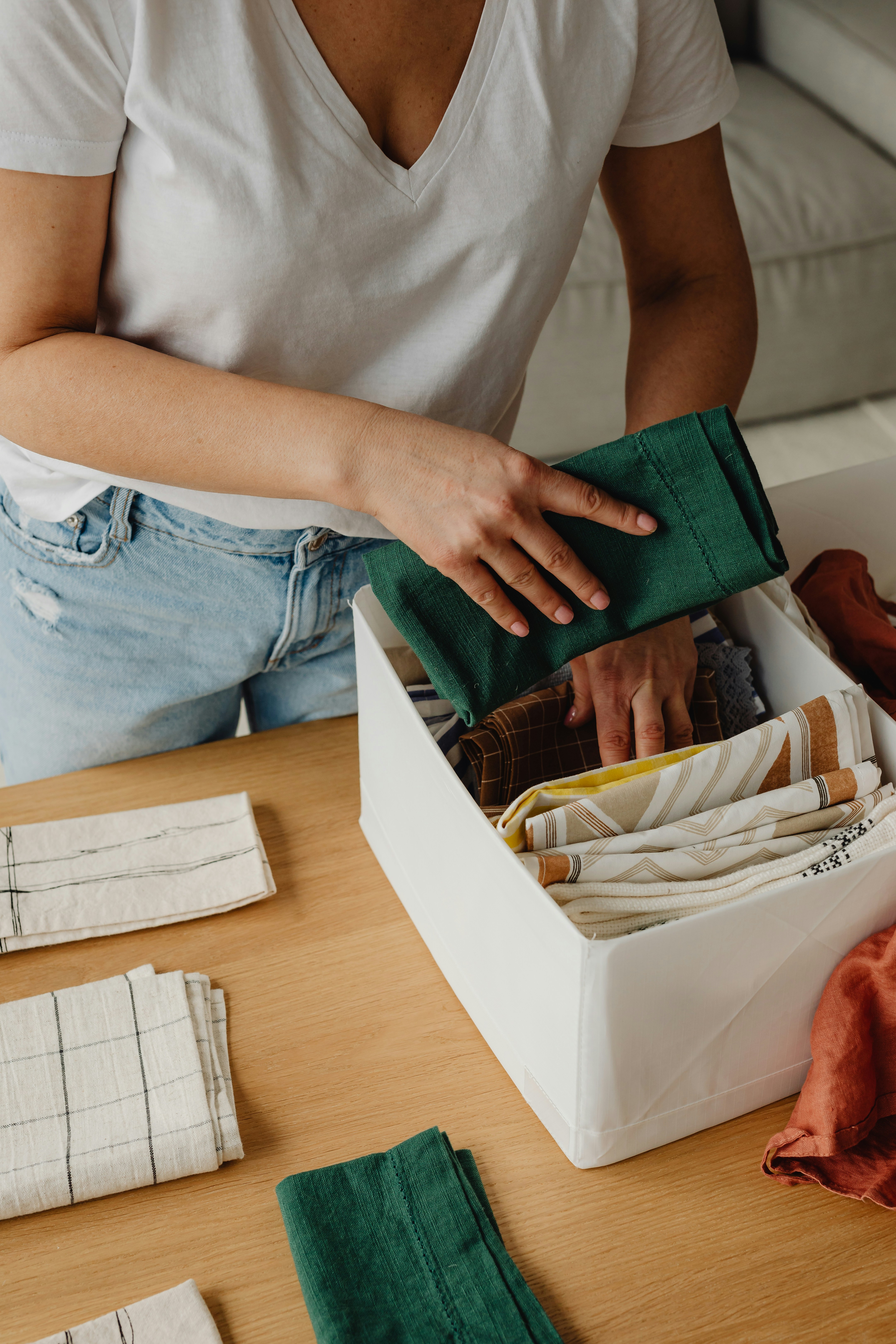 Organisatrice professionnelle triant et rangeant des textiles dans un bac afin d'optimiser l'organisation de la maison.