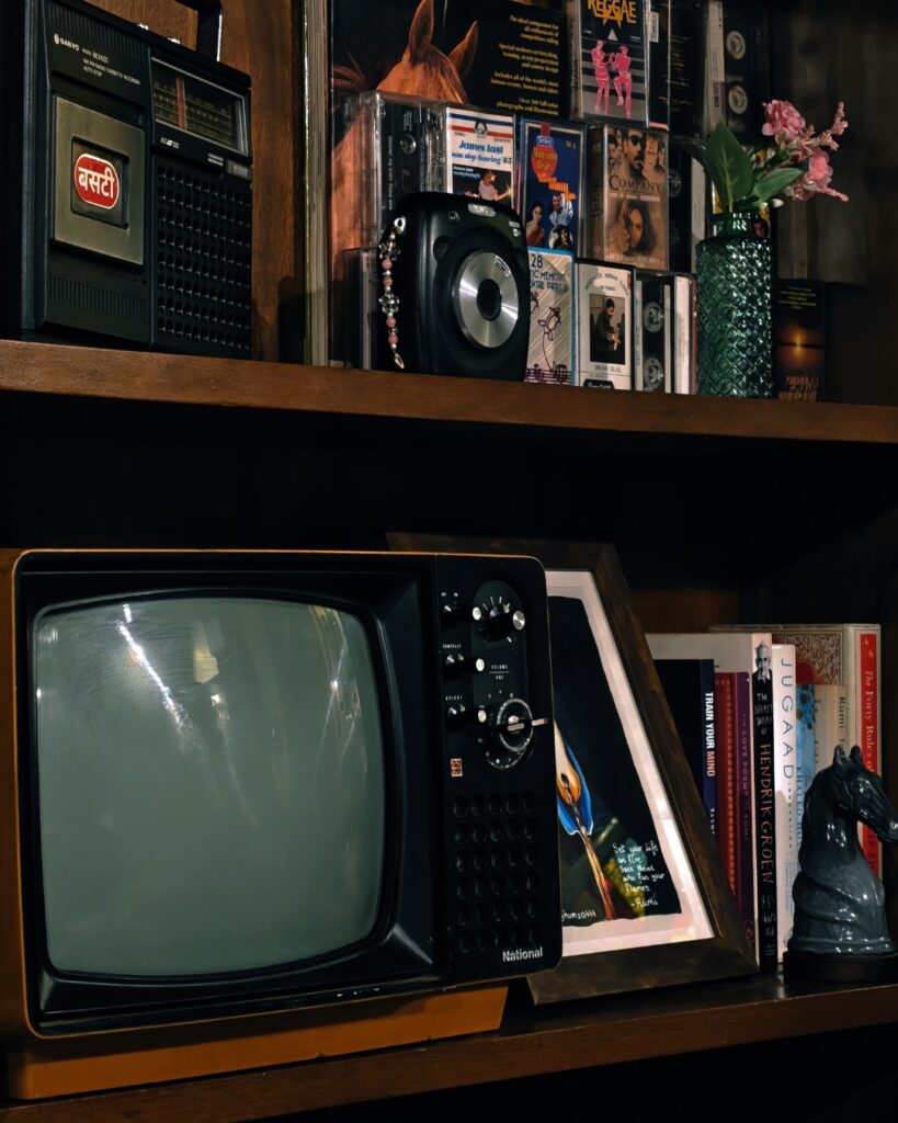 Bibliothèque remplie d'objets anciens, dont une télévision rétro, une radio, des cassettes et des souvenirs, illustrant l'attachement aux objets et la valeur émotionnelle qu'ils peuvent représenter au fil du temps.